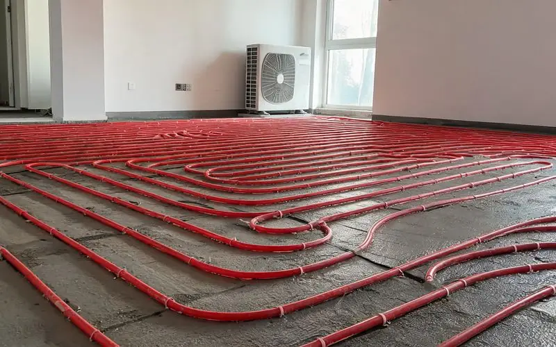 Tuyaux d'un plancher chauffant basse température associés à une pompe à chaleur air-eau dans une maison moderne à Yverdon